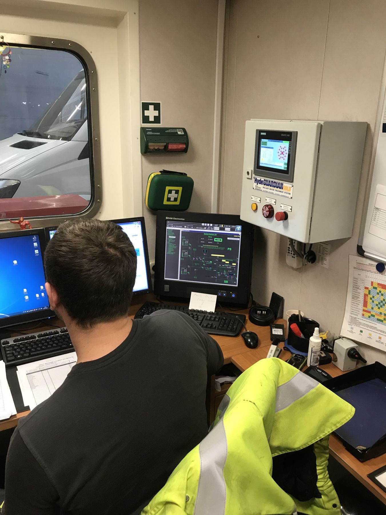 Crew reading BWMS data logs at the ship's computer station