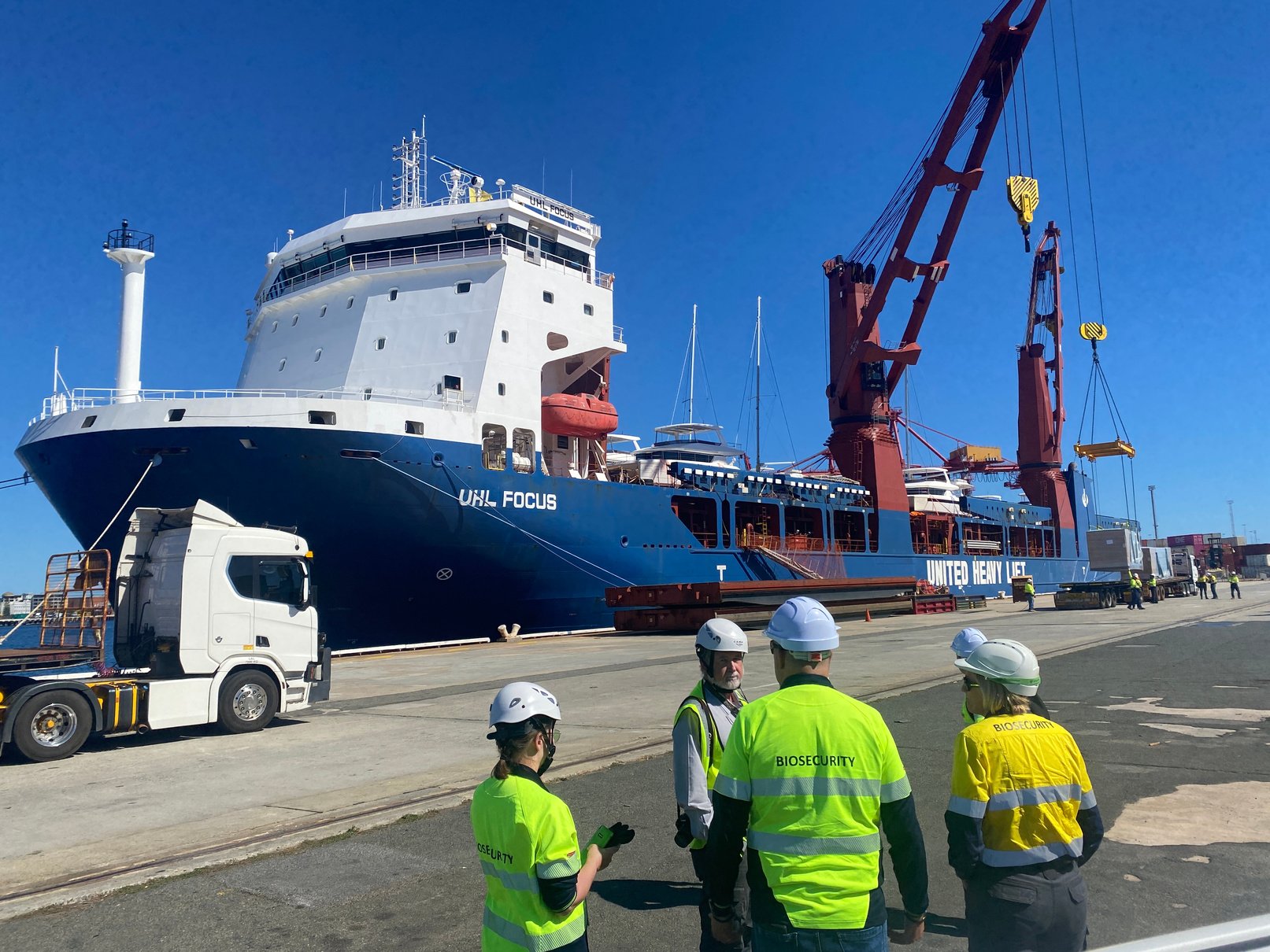 Inspection party in high-visibility gear on the quay beside a vessel